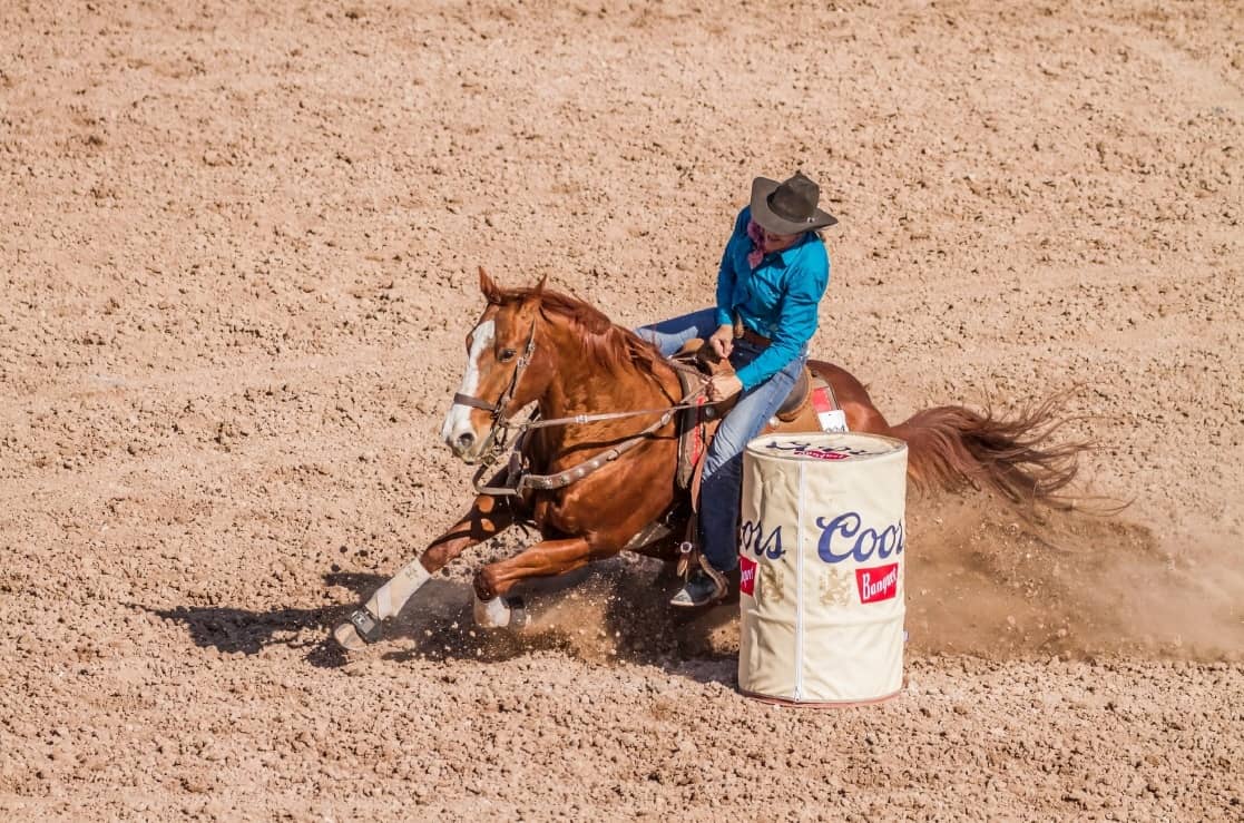 Barrel racer cutting tight around the barrel in the dirt