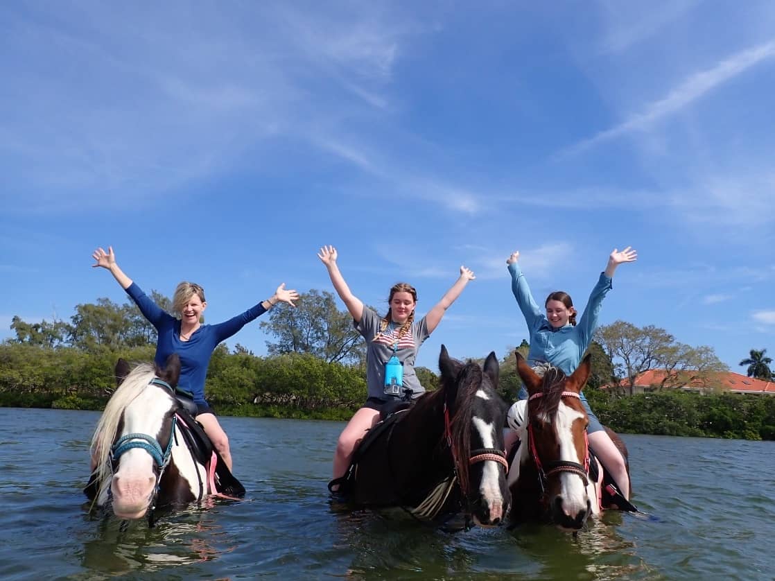 Three riders in open water together, arms thrown up